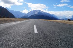 gray asphalt road near mountain range under blue sky during daytime